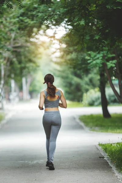 在绿色公园慢跑的年轻女子在小道上慢跑 — 图库照片