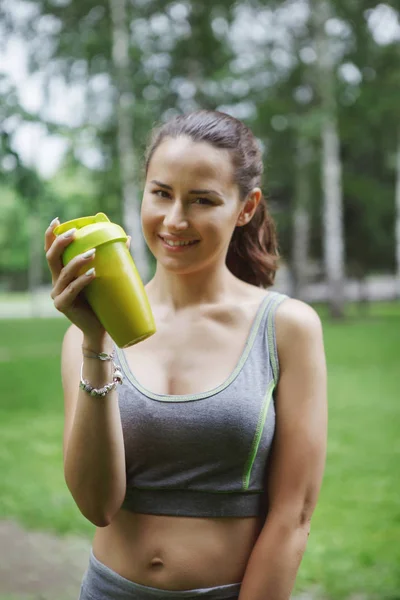 young pretty woman drinking energy drink while jogging