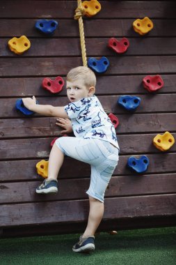 Oğlan mavi T-shirt ve şort duvar tırmanma üzerinde