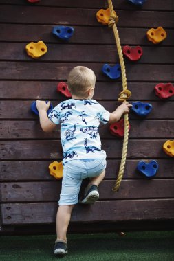 Oğlan mavi T-shirt ve şort duvar tırmanma üzerinde