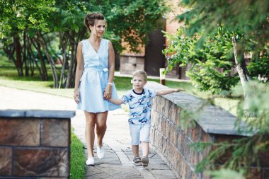 Anne ve sarışın çocuk Park taş kaldırımda yürüyen