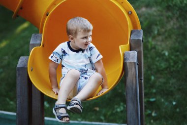 Oğlan mavi tişört Bahçesi sarı slayt tüp sürme içinde