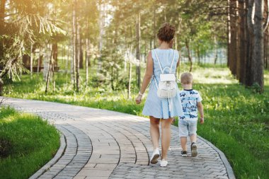 Anne ve sarışın çocuk Park taş kaldırımda yürüyen