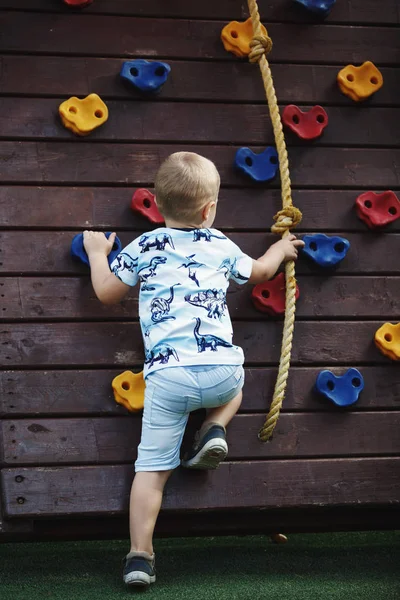Oğlan mavi T-shirt ve şort duvar tırmanma üzerinde