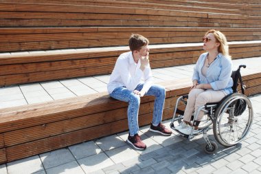 Kadın adamla konuşurken tekerlekli sandalyede şehir parkında adımlar