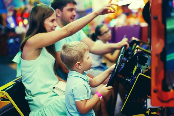 十代の女の子と遊園地でゲーム機で運転して車アーケード少年 — ストック写真