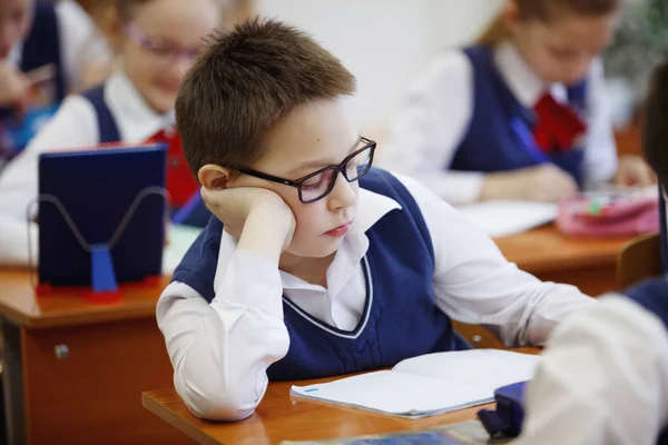 Schüler am Schreibtisch denken und entscheiden die Aufgabe in der Schule. Grundschulbildung, Ausbildung und Personalkonzept — Stockfoto