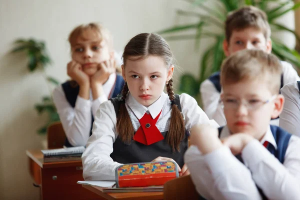 Schüler am Schreibtisch denken und entscheiden die Aufgabe in der Schule. Grundschulbildung, Ausbildung und Personalkonzept — Stockfoto