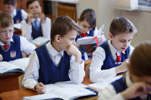 Schüler am Schreibtisch denken und entscheiden die Aufgabe in der Schule. Grundschulbildung, Ausbildung und Personalkonzept — Stockfoto