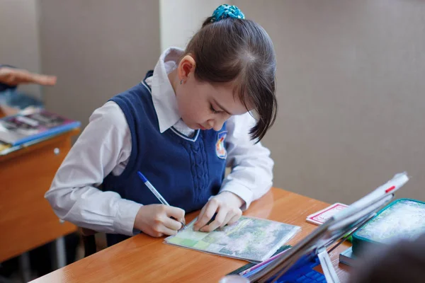 Pupils at the desk think and decide the task in the school. Prim