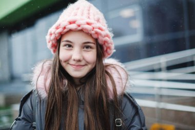 Açık havada gülümseyen genç genç kızın yakın portresi.