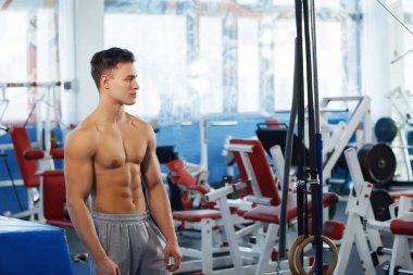 Spor salonunda belirgin bir kas ile genç adam.