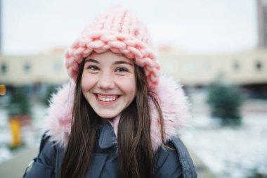 Açık havada gülümseyen genç genç kızın yakın portresi.