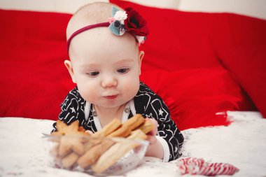 Güzel beş aylık bebek toddler kırmızı bir arka plan üzerinde Noel gingerbread başında mavi elbiseli bir çiçek kız. Anne bakım. Çocuk Bakımı. Yakın çekim.