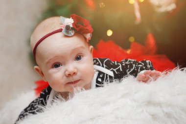 Beyaz ve yeşil arka plan üzerinde mavi bir elbise içinde kafasına bir çiçek ile güzel beş aylık bebek kız. Bebek bakışı. Anne bakımı. Çocuk bakımı. Close.