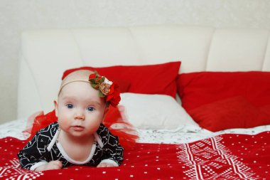 Kırmızı bir arka plan üzerinde baş elbisesi üzerinde bir çiçek ile Lovely beş aylık bebek bebek kız. Anne bakımı. Çocuk bakımı. Genel yukarı.