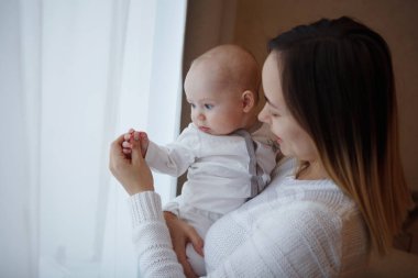Genç mutlu sevgi dolu bir anne ile bebek ellerini cama üzerinde çalış. Anne bakım. Çocuk Bakımı. Yakın çekim.