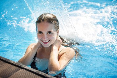 Berrak blu ile bir havuzda bir şelale altında genç güzel kadın