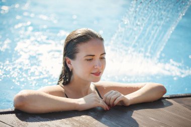 Berrak blu ile bir havuzda bir şelale altında genç güzel kadın