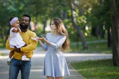 Koyu tenli kız, baba ve anne parkta.
