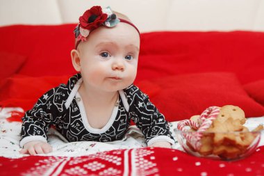 Güzel beş aylık bebek toddler kırmızı bir arka plan üzerinde Noel gingerbread başında mavi elbiseli bir çiçek kız. Anne bakım. Çocuk Bakımı. Yakın çekim.
