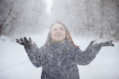 Karlı bir ormanda mavi atkı ve ceket giyen genç, güzel bir kadın..