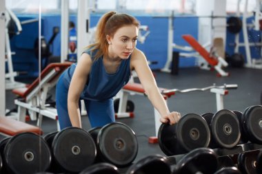 Genç, uzun saçlı, halterleri kaldıran güzel bir kız..