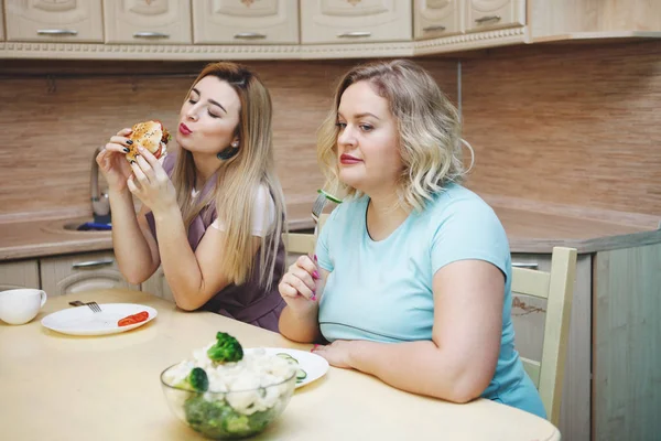 台所で女性の 2 つのガール フレンドの楽しい時を過してそして食糧を食べる. — ストック写真
