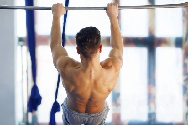 Man making exercises on crossbar. Stock Photo by ©vorobevaola 268566550