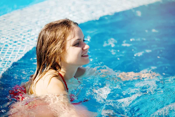 Dos mujeres guapas jóvenes nadan en la piscina con azul claro — Foto de Stock