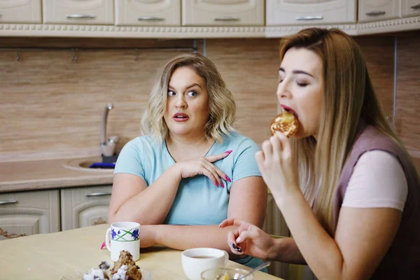 Dos novias mujeres en la cocina se están divirtiendo y comiendo comida . — Foto de Stock