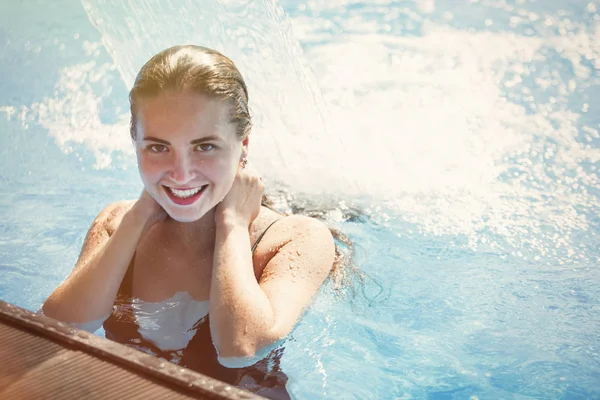 Berrak blu ile bir havuzda bir şelale altında genç güzel kadın