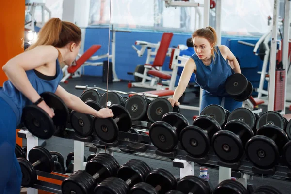 Genç, uzun saçlı, halterleri kaldıran güzel bir kız..