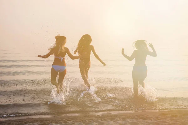 Drie mooie jonge vrouwen rennen naar de zee. — Stockfoto