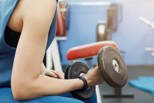 Joven, bonita chica con el pelo largo levantando pesas en el gimnasio . —  Fotos de Stock