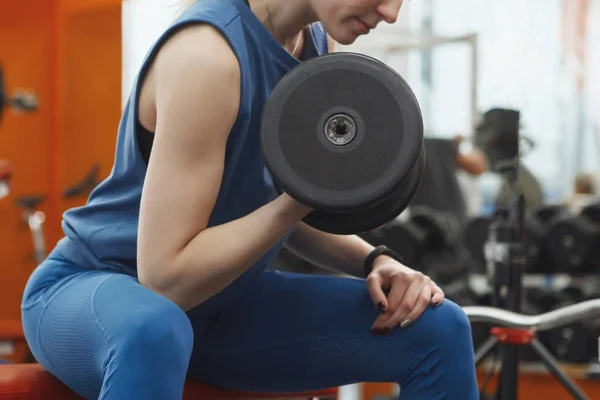 Joven, bonita chica con el pelo largo levantando pesas en el gimnasio . —  Fotos de Stock