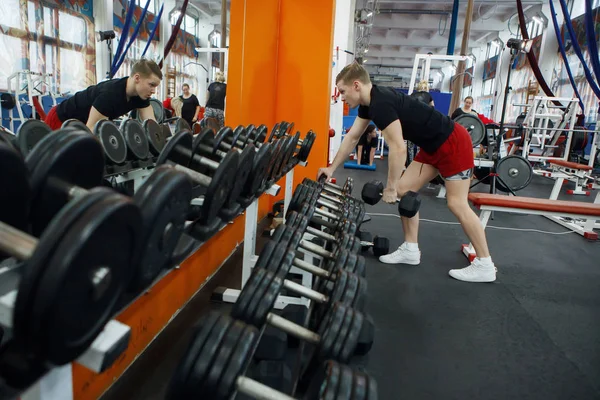 Joven atlético levantando pesas en el gimnasio . — Foto de Stock