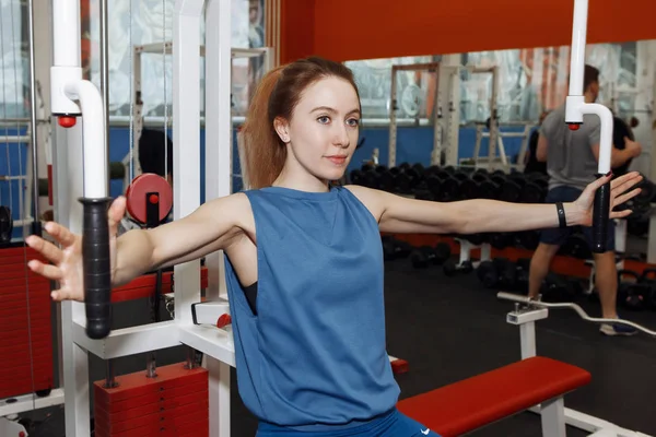 Genç ve güzel bir kadın simülatörde fiziksel egzersiz yapıyor.