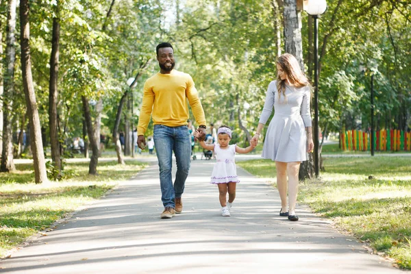 Koyu tenli kız, baba ve anne parkta.