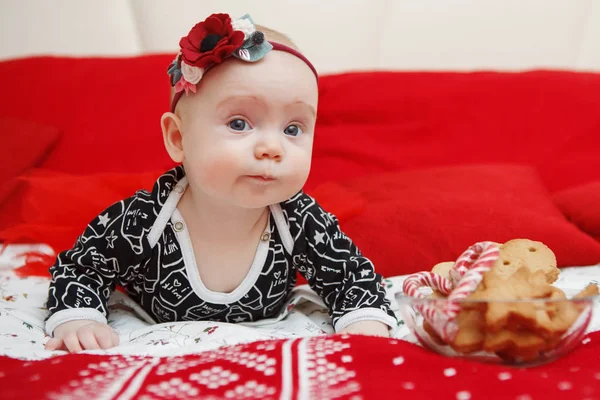 Güzel beş aylık bebek toddler kırmızı bir arka plan üzerinde Noel gingerbread başında mavi elbiseli bir çiçek kız. Anne bakım. Çocuk Bakımı. Yakın çekim.