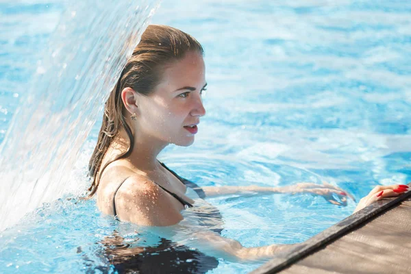 Berrak blu ile bir havuzda bir şelale altında genç güzel kadın