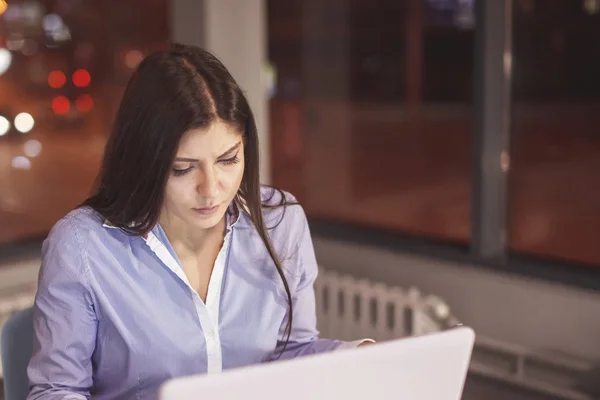 Businesswoman working at the table with a desk lamp.