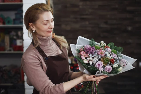 Bir önlük güzel orta yaşlı çiçekçi kadın bir buket toplar.