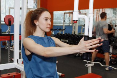 Genç ve güzel bir kadın simülatörde fiziksel egzersiz yapıyor.