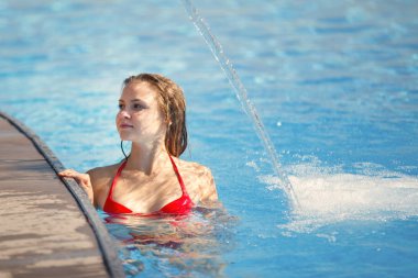 Berrak blu ile bir havuzda bir şelale altında genç güzel kadın