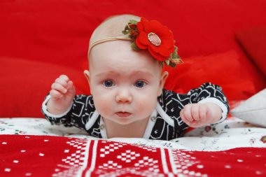 Hoş beş aylık bebek baş elbisesini kırmızı bir arka plan üzerinde bir çiçek kız bebek. Anne bakım. Çocuk Bakımı. Yakın çekim.