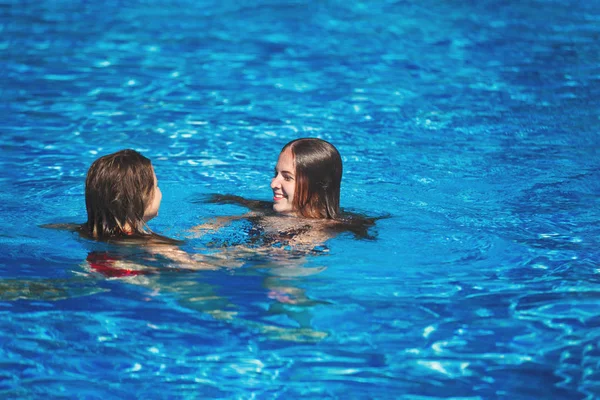 Two young pretty women are swimming in the pool with clear blue — Stock Photo, Image