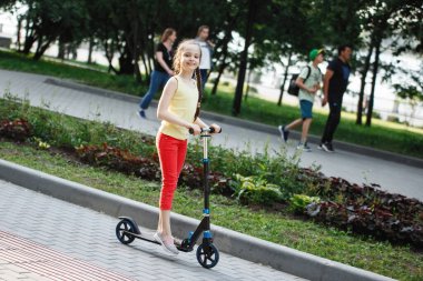 Genç Çocuk, şehir parkında scooter kullanıyor..