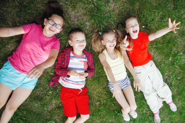 Çocuklar yeşil çimlerin üzerinde yatıyor..