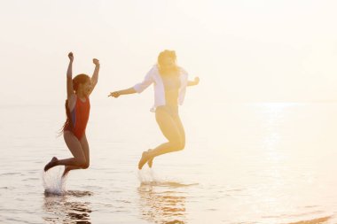 Gün batımında denizde eğlenen iki kız.